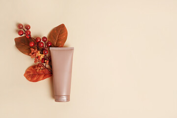 Cosmetic Cream tube mockup with autumn leaves on Beige color background. Natural skincare beauty product concept
