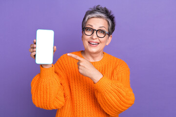 Photo of excited funky woman dressed orange sweater eyewear pointing finger modern device empty space isolated violet color background