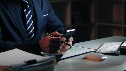 Poster - Asian businessman using smartphone while working overtime at his office room at night.