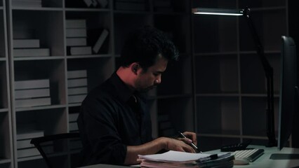 Poster - Tired young Asian businessman working overtime in the office room at night, trying to get things done before the deadline.