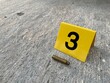 One yellow crime scene evidence marker on the street after a gun shooting brass bullet shell casing rifle