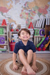 © Tamara Sales  - little boy in a school uniform with books and school supplied in the background