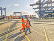 © Connect Images - Team of dock workers walking across dockyard, Felixstowe, England.