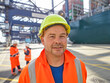 © Connect Images - Portrait of dock worker smiling towards camera wearing hard hat, Felixstowe, England.