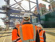 © Connect Images - Candid portrait of three colleagues having meeting in dockyard, one man on smartphone, Felixstowe, England