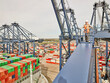© Connect Images - Dock worker looking across dockyard with shipping containers, elevated view from cargo crane, Felixstowe, England