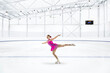 © Connect Images - Young woman in pink dress figure skating at ice rink