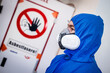 Mann säubert Gebäude von Asbest im blauen Schutzanzug mit gelben Handschuhen und Schutzmaske 