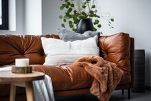 A Detailed View Of A Brown Environmentally Friendly Leather Sofa Adorned With Cozy Cushions And A White Knitted Blanket, Positioned Near A Wall Within An Indoor Room. This Living Room Incorporates A