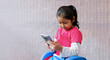 Niña latina emocionada sosteniendo una pantalla de celular en la mano presentando la pantalla vacía del teléfono. Maqueta de pantalla de teléfono inteligente. 