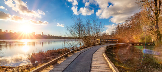 Wall Mural - Wooden pathway in a city park by the lake. Sunset. Deer Lake, Burnaby, Vancouver, BC, Canada