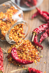 Wall Mural - Crushed and whole chili peppers on wooden table.