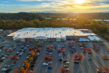 Aerial view of large parking lot in front of rgocery store with many parked colorful cars. Carpark at supercenter shopping mall with lines and markings for vehicle places and directions