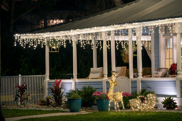 Brightly illuminated christmas decorations on front yard porch of florida family home. Outside decor for winter holidays