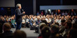 © Bnetto - Speaker performing on stage with spotlight talking to many people in audience, event professional.