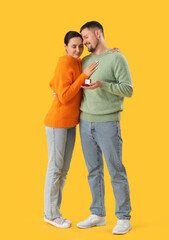 Poster - Young man proposing to his girlfriend on yellow background