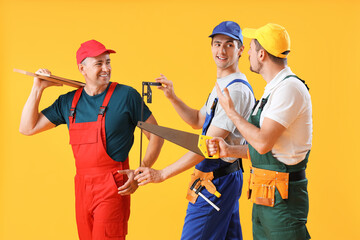 Canvas Print - Team of male builders with tools on yellow background