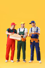 Canvas Print - Team of male builders with wallpapers on yellow background