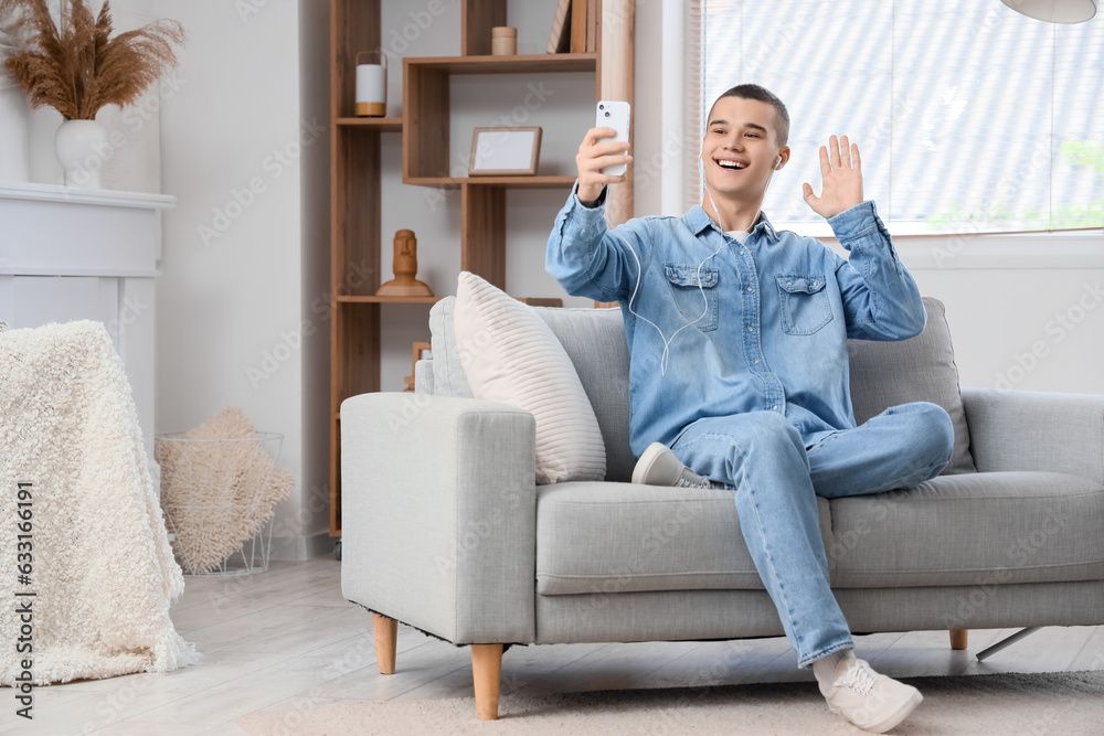 Young man with mobile phone video chatting at home