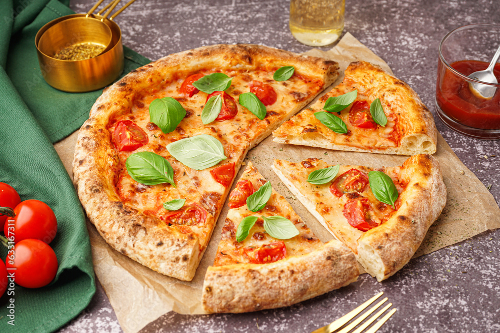 Baking paper with tasty pizza Margarita and basil on dark table