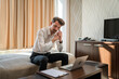 © Miljan Živković - One man adult Caucasian male work from hotel room make a call on phone