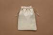 Burlap bag on brown background, top view