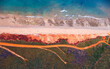 Aerial view of red sandy coastline and dirt track along turquoise water at Dampier Peninsula, Broome, Western Australia