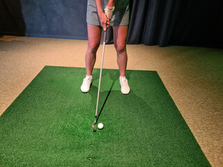 Wall Mural - Professional female golfer playing golf indoors on golf simulator closeup