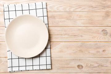 top view on colored background empty round white plate on tablecloth for food. empty dish on napkin 