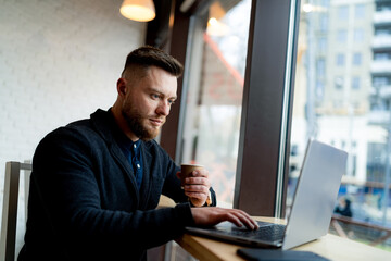 Man working on a laptop at a table. A man sitting at a table using a laptop computer