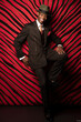 © GraphicsRF - Confident African man in a stylish zoot suit and fedora, striking a relaxed pose with a bright white smile.