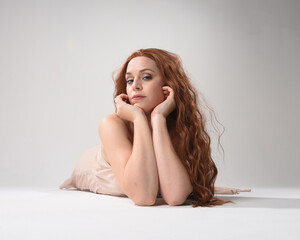 Sticker - Full length portrait of beautiful brunette model  wearing a  pink dress. graceful sitting  pose, kneeling on floor gestural hands. shot from low angle perspective,  isolated on white studio background