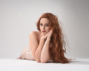 Sticker - Full length portrait of beautiful brunette model  wearing a  pink dress. graceful sitting  pose, kneeling on floor gestural hands. shot from low angle perspective,  isolated on white studio background