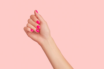 Poster - Womans hand with trendy manicure on pastel pink background. Beauty salon concept