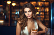 © Anoo - Beautiful young woman sitting at a bar with a glass of whiskey in a luxurious interior. Blurred background. A woman is relaxing in a bar with a glass.