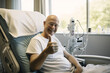 © wolfhound911 - Bald mature man smiling in cancer hospital bed .