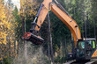 Wood chipper is chopping wood on side of road using mulching attachment on an excavator.