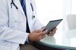Male doctor using a digital tablet while sitting in the office.
