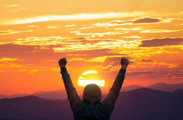 Wall Mural - the sun in the morning, praying. a silhouette of a happy men enjoying the sun on an orange background. dawn in the mountains. Boy with arms outstretched, beaming at the early-morning sun.