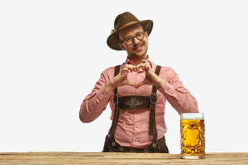 Wall Mural - Portrait of man wearing a traditional german outfit showing heart symbol shape feelings on holiday event. Concept of Oktoberfest