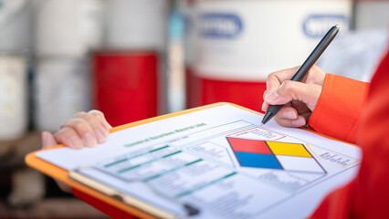 Wall Mural - a safety officer is checking on the hazardous material checklist form with chemical storage area at 