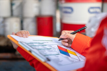 Wall Mural - a safety officer is checking on the hazardous material checklist form with chemical storage area at 