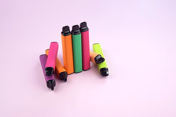 Wall Mural - Set of multicolor disposable electronic cigarettes on a pink background.