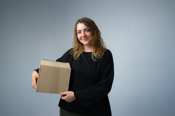 Happy woman moving in carrying cartons boxes with red paper house and key. Young girl arranging interior and unpacking at new apartment home.