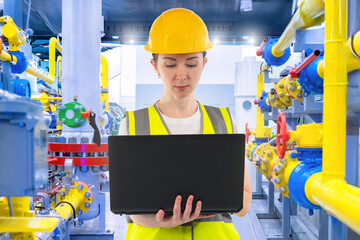 Poster - Woman employee of chemical factory. Girl industrialist with laptop. Woman stands in room with pipes. Chemical production. Engineer at gas distribution station. Lady engineer working in factory