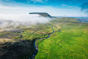 Ancient valley with volcanic mountain and fog in remote wilderness in summer