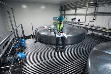 Male work inspection process stainless steel tanks and pipe with pressure meter in equipment tank facility for milk cellar at the with vertical stainless