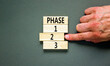 Time to phase 2 symbol. Concept word Phase 1 2 3 on wooden block. Businessman hand. Beautiful grey table grey background. Business planning and time to phase 2 concept. Copy space.