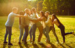 © Studio Romantic - Full length portrait of a funny happy overjoyed students friends having fun in nature in the summer park pushing each other enjoying time together at sunny day. Team building and friendship concept.