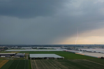 Wall Mural - aerial view of a daytime lightning strike over an agricultural are with greenhouses in the netherlan